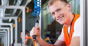 A man smiling whilst working on an assembly line